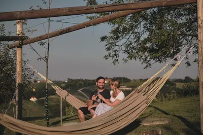 a man and a woman sitting in a hammock at Holiday house Podhamer Boris in Presika