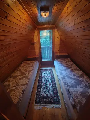 an attic room with two beds and a window at KOČA PLANIKA, SVIŠČAKI in Ilirska Bistrica
