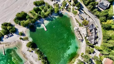 an aerial view of a beach with a green lake at JASNA NATUR Resort by the lake in Kranjska Gora