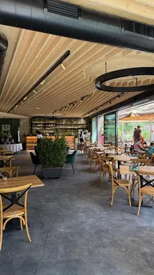 a restaurant with wooden tables and chairs and people at JASNA NATUR Resort by the lake in Kranjska Gora