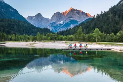 a group of people riding bikes on a bridge over a lake at JASNA NATUR Resort by the lake in Kranjska Gora