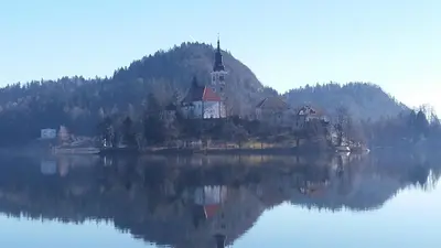a church on an island in the middle of a lake at Apartments and rooms Brunko in Bled