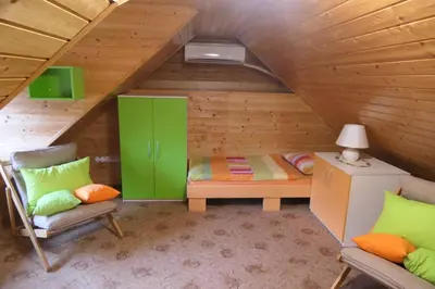 a room with a bed and two chairs in a attic at Apartments and rooms Brunko in Bled