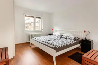 a white bedroom with a bed and a window at Island View Apartment in Bled