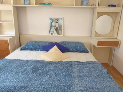 a bedroom with a bed with a blue blanket and pillows at APARTMENT PRIMČEVA in Maribor