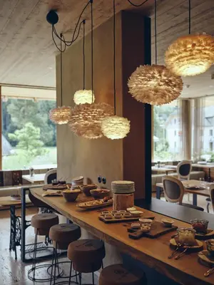 a dining room with a table and chairs and lights at Boutique hotel Vila Planinka in Zgornje Jezersko
