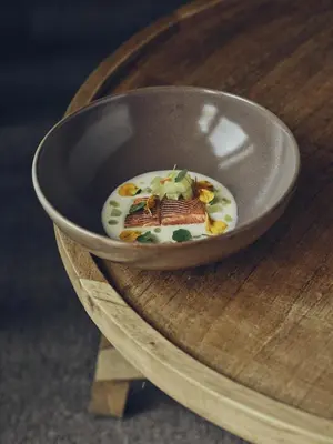 a bowl of food sitting on a wooden table at Boutique hotel Vila Planinka in Zgornje Jezersko