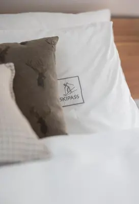 a pillow on a bed with a sticker on it at Boutique Skipass Superior Hotel in Kranjska Gora