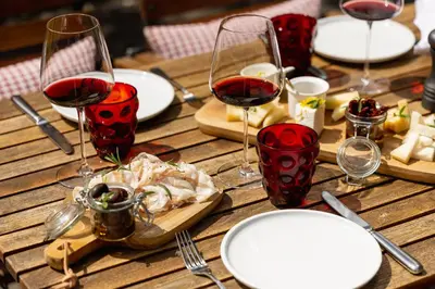 a wooden table with wine glasses and a plate of food at Boutique Skipass Superior Hotel in Kranjska Gora