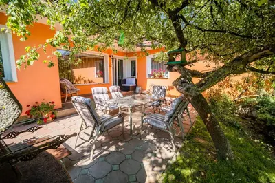 a patio with a table and chairs under a tree at Apartment Tina with Seasonal Pool in Podsreda