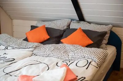 a bed with orange and black pillows on it at Apartment Tina with Seasonal Pool in Podsreda