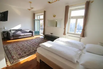 a bedroom with two beds and a living room at Hotel Vila Katrca in Ljubljana