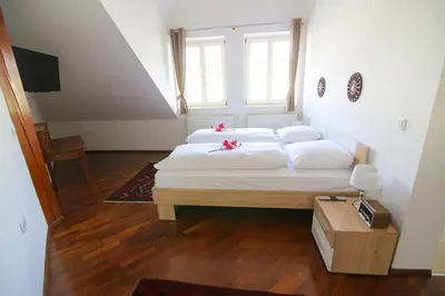 a bedroom with a bed with white sheets and a window at Hotel Vila Katrca in Ljubljana