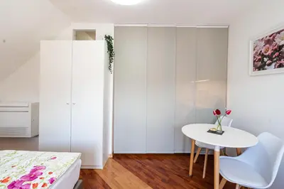 a white bedroom with a table and a bed at Rooms Močilnik in Begunje na Gorenjskem