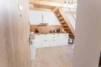 a kitchen with white cabinets and a wooden floor at Rooms Močilnik in Begunje na Gorenjskem