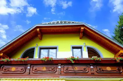 a yellow house with windows and flowers on it at Rooms Močilnik in Begunje na Gorenjskem
