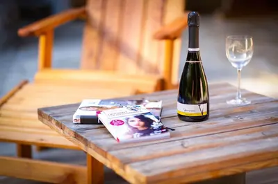 a bottle of wine sitting on a wooden table with a glass at Chalet Letnik in Žiri