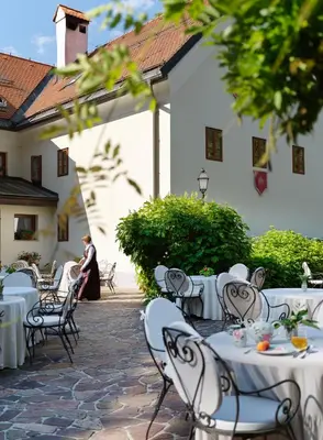 a group of tables and chairs in front of a building at Kendov Dvorec in Spodnja Idrija