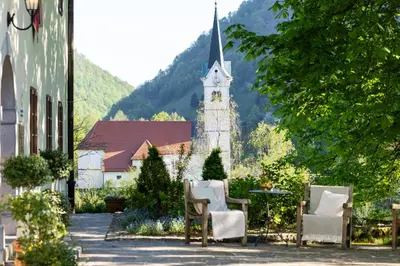 a church with a clock tower and two chairs at Kendov Dvorec in Spodnja Idrija