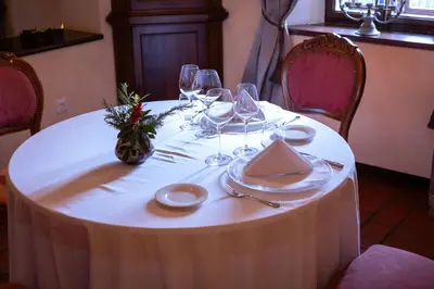 a table with a white table cloth and wine glasses at Kendov Dvorec in Spodnja Idrija