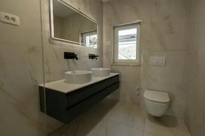 a bathroom with two sinks and a toilet at Bed & Breakfast Adelsberg Inn in Postojna