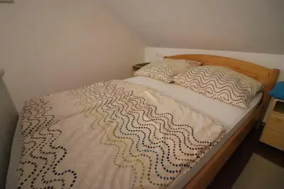 a bedroom with a bed with a wooden headboard at Pod Orehi Guest House in Loče pri Poljčanah