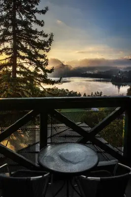 a table and chairs on a balcony with a view of a river at Hotel Triglav in Bled