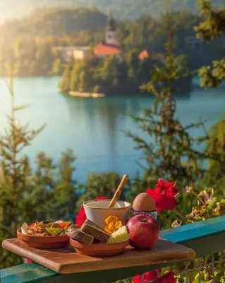 a tray of food on a table with a view of a lake at Hotel Triglav in Bled