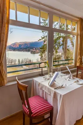 a dining room with a table and a large window at Hotel Triglav in Bled