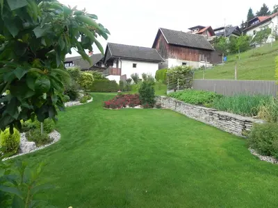 a yard with green grass and a retaining wall at Apartments Vesna in Bled