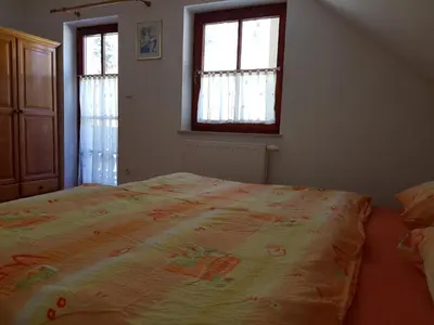 a large bed in a bedroom with two windows at Vaznik Farm House Apartments in Bled