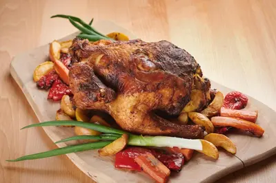 a plate of meat and vegetables on a wooden table at Eco Tourist Farm Ravnjak in Slovenj Gradec