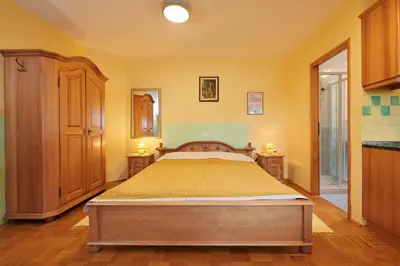 a bedroom with a bed with yellow walls and wooden floors at Eco Tourist Farm Ravnjak in Slovenj Gradec
