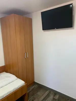 a room with a bed and a cabinet with a flat screen tv at Apartman Decorus in Maribor