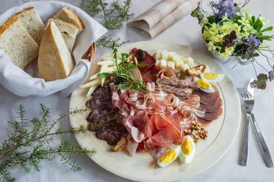 a plate of food with meat and cheese and bread at EkoTurizem Hudičevec in Postojna