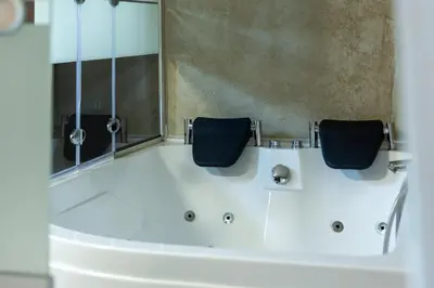 a bathroom with a tub with two chairs in it at Apartments Silva in Ljutomer