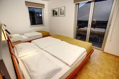 two beds in a room with a large window at Primula Accommodation in Nova Gorica