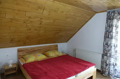 a bedroom with a red bed with a wooden ceiling at BOOA Rooms Irena in Bohinj