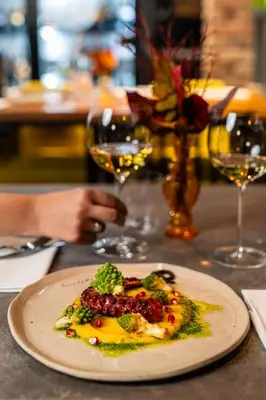 a plate of food on a table with wine glasses at Bužinel Estate in Dobrovo