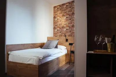 a bedroom with a wooden bed with a brick wall at Bužinel Estate in Dobrovo