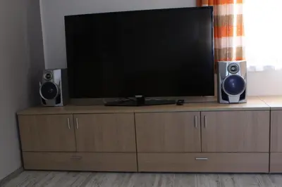 a flat screen tv on a wooden entertainment center with two speakers at Apartma Lipa in Mojstrana