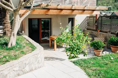 a patio with a wooden pergola next to a house at Apartment House Blazar in Tolmin