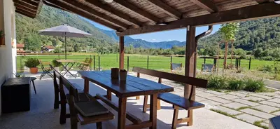 a wooden table with chairs and an umbrella on a patio at Apartment House Blazar in Tolmin