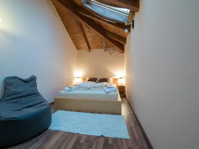 a small bedroom with a bed and a blue chair at Vila Bovec Sky mansard apartment in Bovec