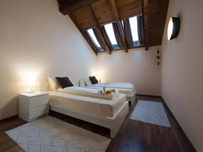 two beds in a room with two windows at Vila Bovec Sky mansard apartment in Bovec