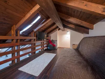 a bedroom with a bed and a tv and wooden ceilings at Vila Bovec Sky mansard apartment in Bovec