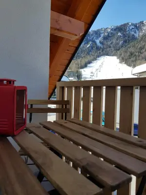 a wooden bench on a balcony with a view of a ski slope at Vila Mojca SKI IN&OUT - Apartmaji Lena in Kranjska Gora