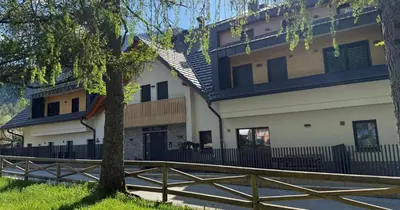 a building with a fence next to a tree at Vila Mojca SKI IN&OUT - Apartmaji Lena in Kranjska Gora