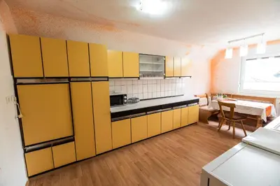 a kitchen with yellow cabinets and a dining room at Apartment Carmen in Brezje