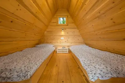 two beds in a log cabin bedroom with wooden floors at Glamping Village - Speleo Camp in Logatec
